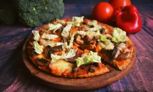 Pyszna pizza z twarogu z pieczarkami i kapustą pekińską, obok brokuły i pomidory.