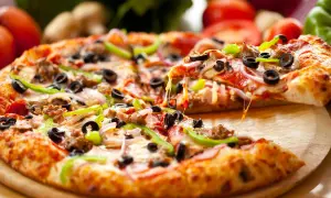 Pyszna pizza na gotowym spodzie z serem, oliwkami, papryką i salami. Ciągnący się ser zachęca do spróbowania.