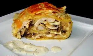 Pyszna pierś z kurczaka w cieście francuskim z pieczarkami i serem, podana z sosem.