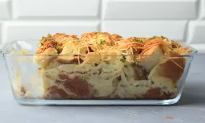 Pyszna zapiekanka z chleba i jajek w piekarniku, posypana serem i ziołami. Idealna na śniadanie lub kolację.
