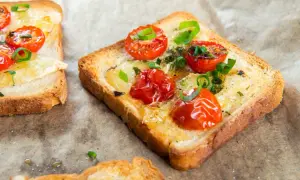 Pyszna, szybka kolacja na ciepło: tosty z roztopionym serem, pomidorkami koktajlowymi i szczypiorkiem.
