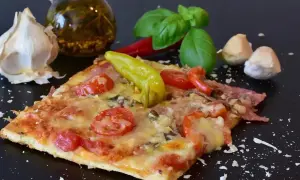 Pyszny kawałek pizzy z pomidorami i papryką, czosnkiem i bazylią. Zastanawiasz się, ile może leżeć pizza w lodówce?