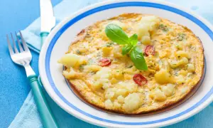 Omlet z kalafiorem i pomidorkami, idealny na lekki obiad. Udekorowany listkiem bazylii.
