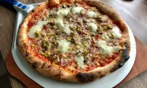 Gorąca pizza salami z roztopionym serem, oliwkami i pieczarkami, gotowa do podania.