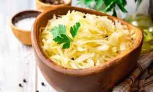 Miseczka z kapustą kiszoną, ozdobiona natką pietruszki. Dowiedz się, ile gotować kapustę kiszoną, by była idealna.