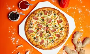 Pyszna pizza z kiełbasą, pieczarkami i oliwkami. Obok sosy, czosnek i imbir – idealne składniki na pizzę.