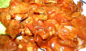Karkówka w sosie pomidorowym z piekarnika, duszona z cebulą i pieczarkami, podana na liściach sałaty.