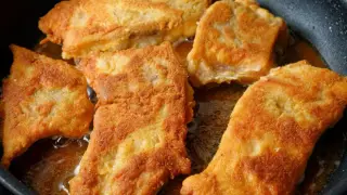Pięć kawałków panierowanego mięsa smażonego na złoty kolor w głębokim oleju na patelni.