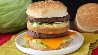 Domowy Big Mac z dwoma kotletami, serem, sałatą i sosem na talerzu.