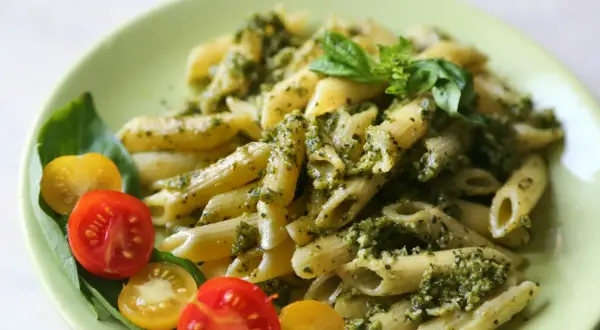 Penne z pesto i pomidorkami koktajlowymi – idealny letni obiad. Świeża bazylia dodaje aromatu.