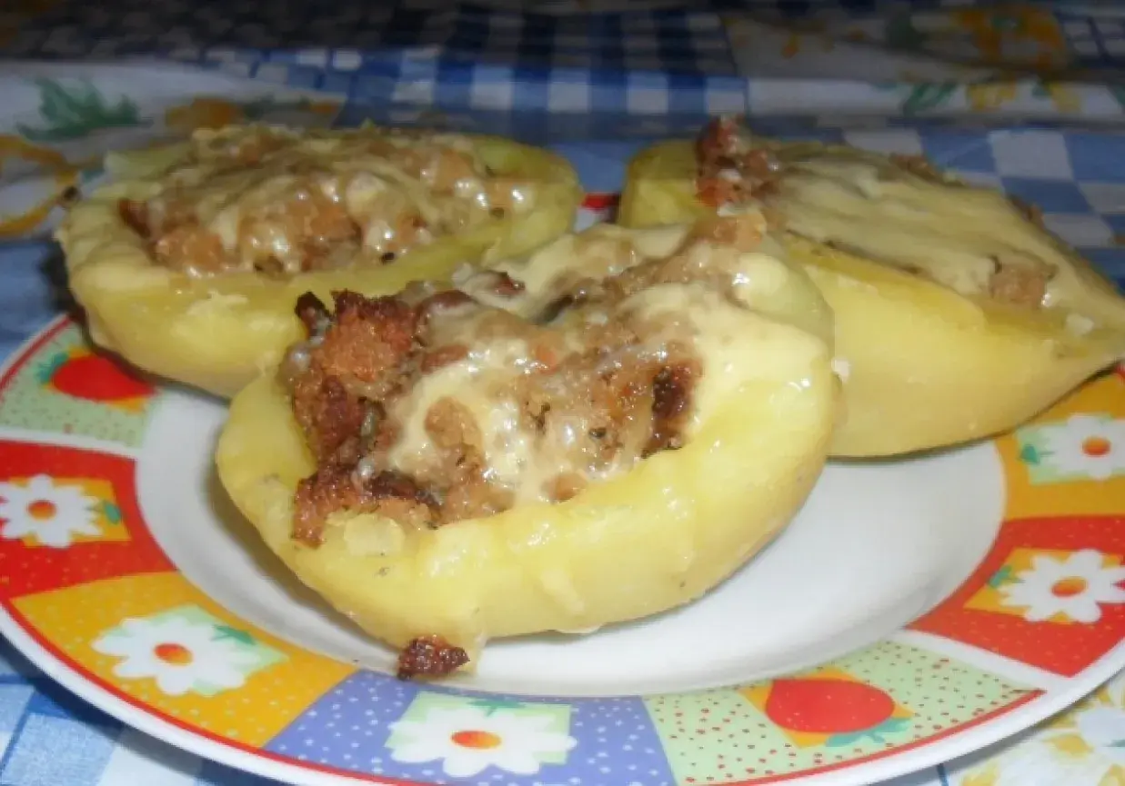 Surowe ziemniaki faszerowane mięsem mielonym, zapieczone z serem. Pyszne danie na talerzu.