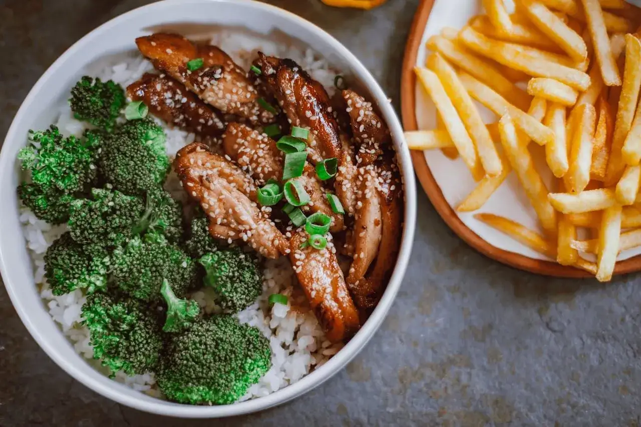 Pyszny obiad z air fryera: kurczak teriyaki z ryżem i brokułami, obok frytki. Idealne air fryer przepisy na obiad.