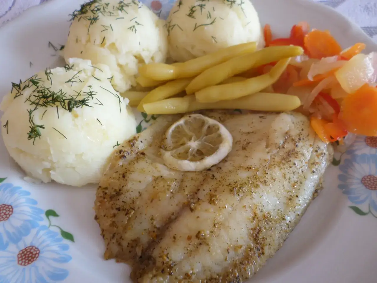 Pyszna ryba gotowana z ziemniakami, fasolką i surówką z marchewki.