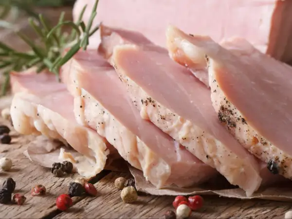Kawałki super delikatnego i soczystego schabu gotowanego, przyprawione pieprzem, z gałązką rozmarynu.