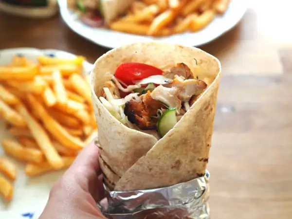 Pyszny kebab amerykański z kurczakiem, warzywami i frytkami na talerzu.