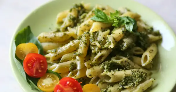 Penne z pesto i pomidorkami koktajlowymi – idealny letni obiad. Świeża bazylia dodaje aromatu.